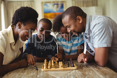 Family playing chess together at home in the living room