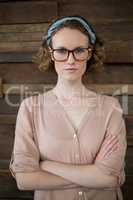 Confident female business executive standing with arms crossed in office