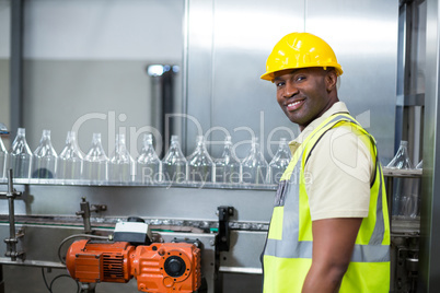 Smiling factory worker standing next to production line