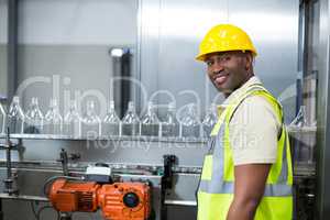 Smiling factory worker standing next to production line