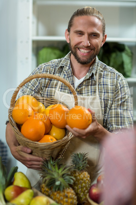 Smiling vendor offering oranges at the counter