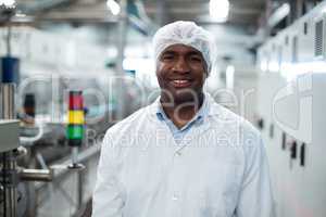 Smiling factory engineer standing in bottle factory