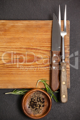 Knife and fork on wooden board