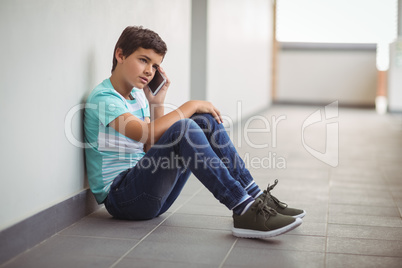 Schoolboy talking on mobile phone in corridor