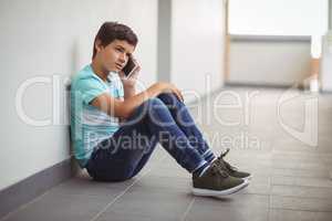 Schoolboy talking on mobile phone in corridor