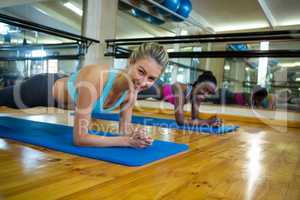 Two fit women doing stretching exercise on mat