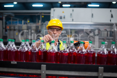 Male factory worker monitoring cold drink bottles