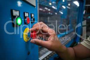 Hands of factory worker turning the control knob on the board
