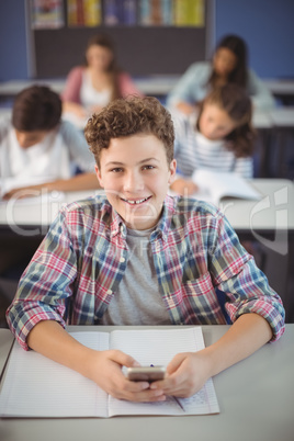 Student holding mobile phone in classroom