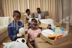 Parents and kids unboxing cardboard boxes in living room