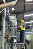 Male factory worker maintaining record on clipboard