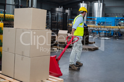 Factory worker pulling trolley of cardboard boxes