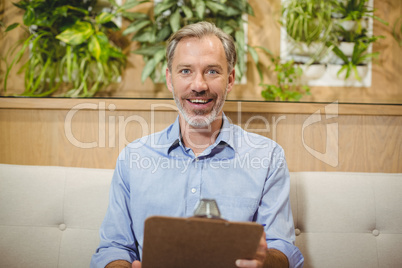 Smiling doctor holding clipboard in clinic