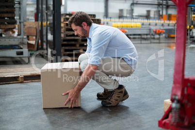 Factory worker picking up cardboard boxes in factory