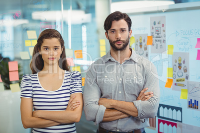 Portrait of male and female executives standing with arms crossed