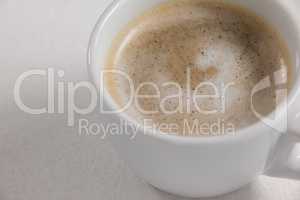 Close-up of white coffee cup with creamy froth
