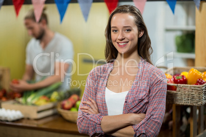 Smiling woman vendor standing in the grocery store with arms crossed