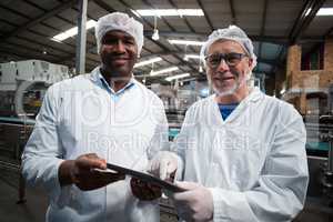Two factory engineers with digital tablet smiling in the drinks production plant