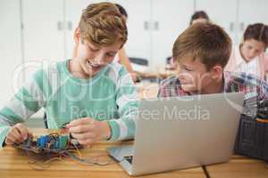 Smiling schoolboys working on electronical project in classroom