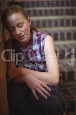 Sad schoolgirl sitting alone on staircase