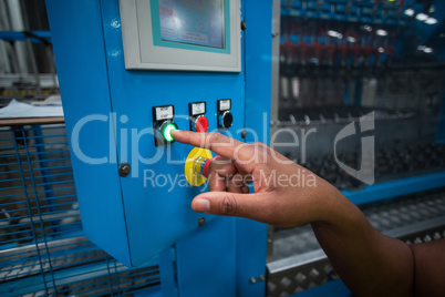 Hands of factory worker pressing a green button on the control board