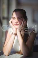 Thoughtful schoolgirl sitting in classroom