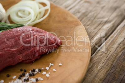 Beef steak, salt and onions on wooden tray against wooden background