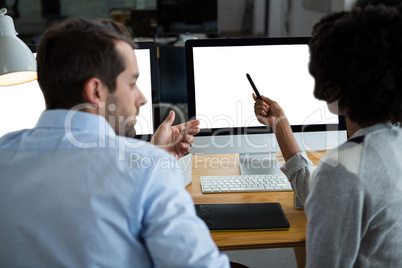 Man and woman discussing over desktop pc