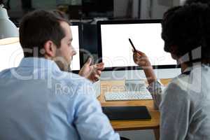 Man and woman discussing over desktop pc