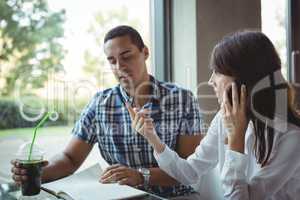 Executives talking on mobile phone while discussing on diary