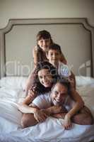 Happy family stacking on top of each other on the bed