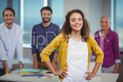 Portrait of smiling graphic designer standing with her colleagues in background