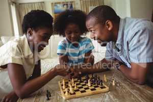 Family playing chess together at home in the living room