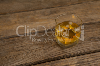 Glass of whisky with ice on wooden table