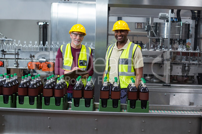 Portrait of two factory workers monitoring cold drink bottles in the plant