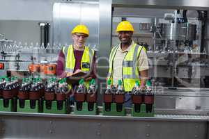 Portrait of two factory workers monitoring cold drink bottles in the plant