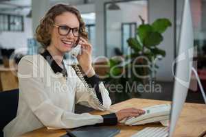 Woman talking on landline phone at desk
