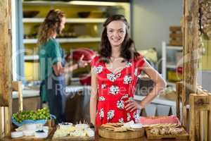 Portrait of smiling female customer standing with hands on hip at counter