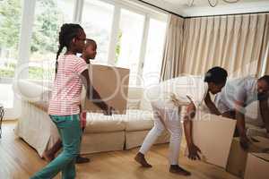 Parents and kids carrying cardboard boxes in living room