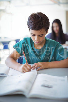 Schoolboy doing homework in classroom