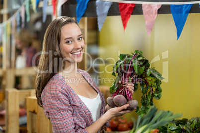 Smiling woman choosing vegetables in grocery store