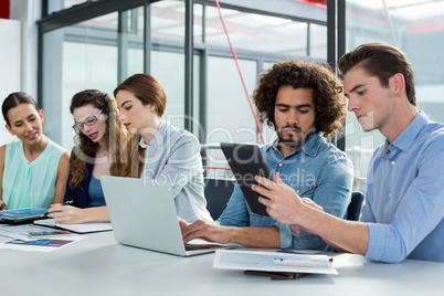 Business team discussing over laptop and digital tablet in meeting