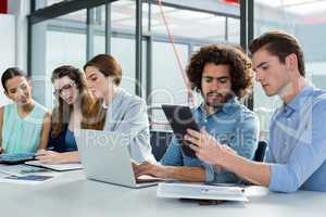 Business team discussing over laptop and digital tablet in meeting