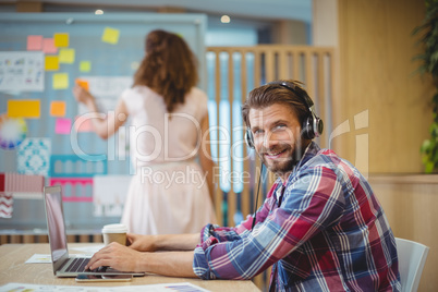 Portrait of business executive listening song while using laptop