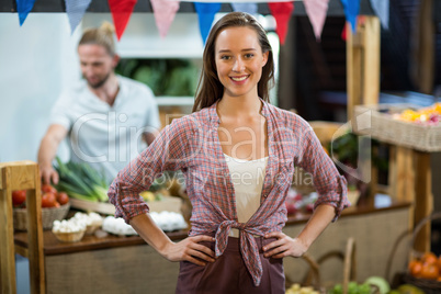 Smiling woman vendor standing in the grocery store with hands on hips