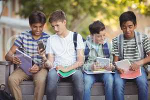 School kids using mobile phone and digital tablet on bench