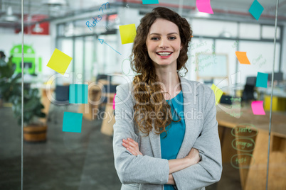 Smiling female executive standing with arms crossed in creative office