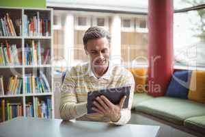 Attentive school teacher using digital tablet in library