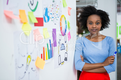 Female graphic designer standing with hands crossed in creative office