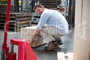 Portrait of factory worker picking up cardboard boxes